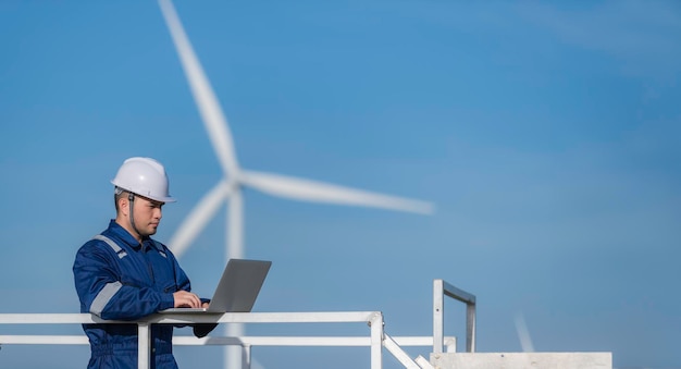 Due ingegneri che lavorano e tengono il rapporto alla stazione di generazione di energia della fattoria di turbine eoliche sulla montagna della Thailandia uomo e donna tecnici discutono del lavoro