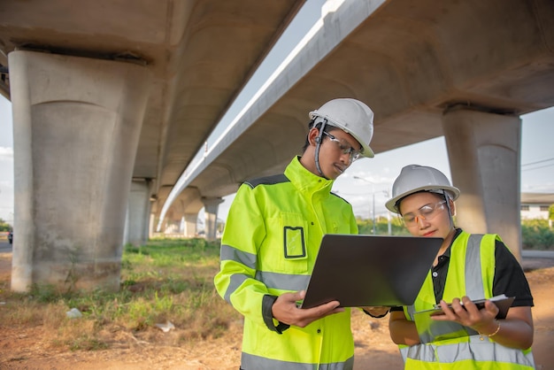 Due ingegneri discutono del lavoro nel sito del grande ponte in costruzioneConsulenza della gestione delle persone Discussione con gli ingegneri sullo stato di avanzamento e sulla pianificazione della costruzione dell'autostrada