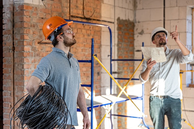 Due ingegneri edili che parlano in cantiere, ingegnere che spiega un disegno a un lavoratore.