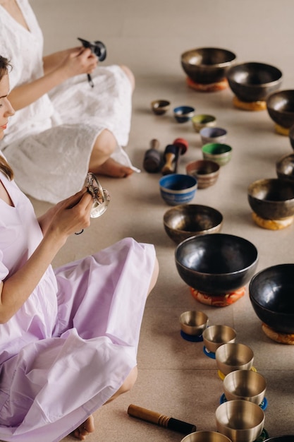 Due insegnanti di yoga giocano su ciotole tibetane in palestra durante un ritiro di yoga