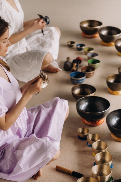 Due insegnanti di yoga giocano su ciotole tibetane in palestra durante un ritiro di yoga