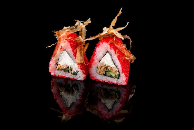 Due involtini di tonno rosso con caviale rosso e gamberi su sfondo nero con riflesso. Primo piano, vista dall'alto. Concetto di consegna del cibo.