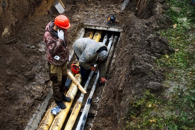 Due lavoratori cambiano le condutture dell'acqua pubblica in trincea in una piovosa giornata autunnale