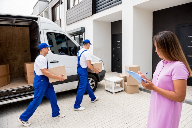 Due lavoratori dell'azienda di traslochi scaricano scatole dal minibus a casa dei clienti