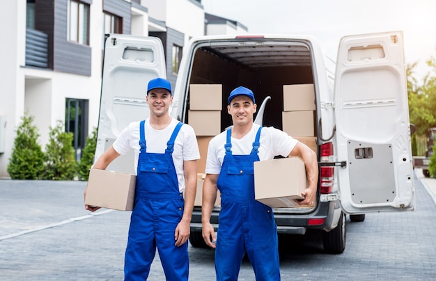 Due lavoratori dell'azienda di traslochi scaricano scatole dal minibus a casa dei clienti