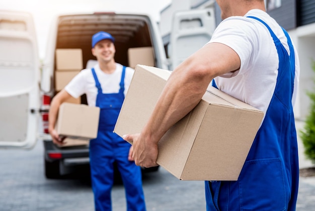Due lavoratori dell'azienda di traslochi scaricano scatole dal minibus a casa dei clienti