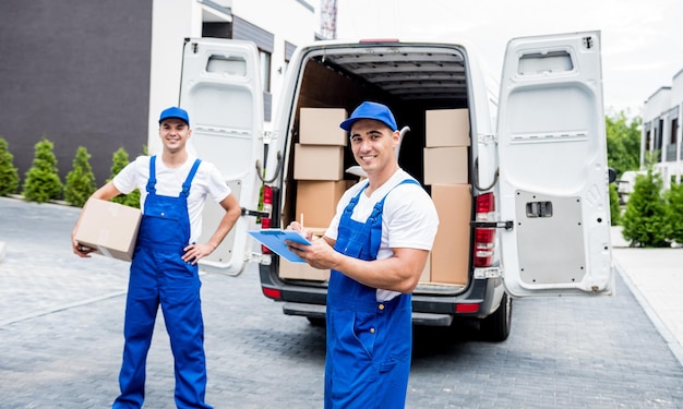 Due lavoratori di una società di traslochi scaricano scatole dal minibus a casa dei clienti