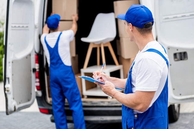 Due lavoratori di una società di traslochi scaricano scatole dal minibus nella nuova casa