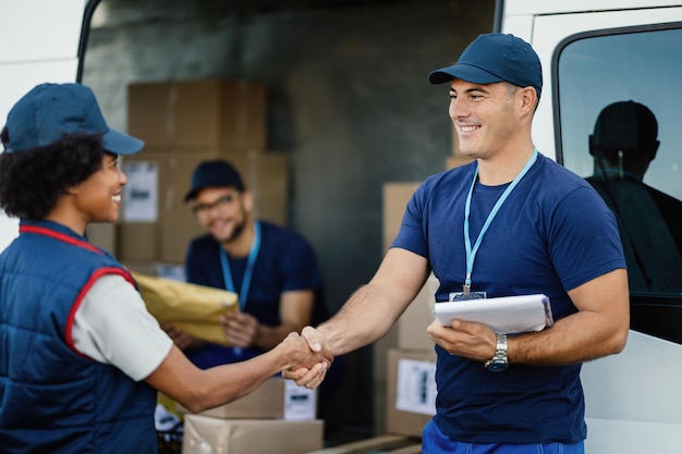 Due lavoratori manuali felici che si stringono la mano con il furgone di consegna Focus è sull'uomo