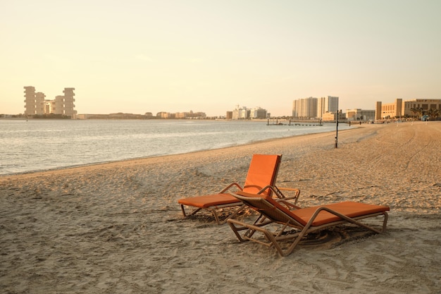 Due lettini arancioni si trovano in riva al mare al tramonto serale Dubai UAE Il Royal Atlantis Dubai sul retro