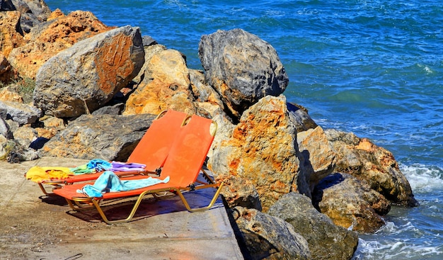 Due lettini rossi sulla spiaggia con il mare sullo sfondo