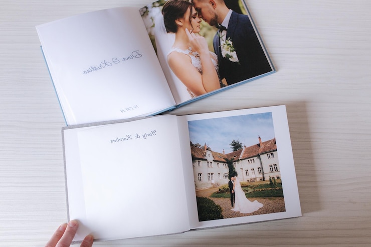 Due libri fotografici aperti con lo sposo e la sposa sul tavolo di legno bianco Confronto