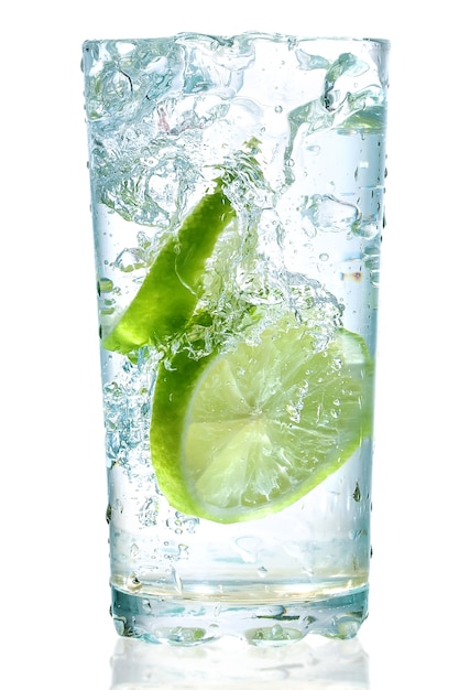 Due lime caddero in un bicchiere con acqua isolato su bianco