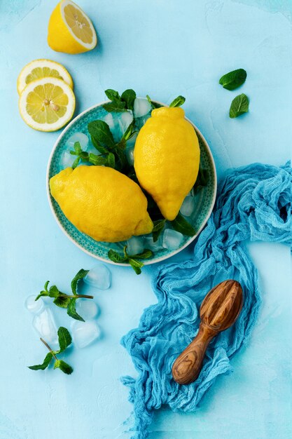 Due limoni freschi nel piatto blu su sfondo di cemento turchese. Sfondo di cibo. Vista dall'alto.