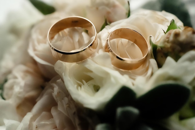 Due lussuose fedi nuziali dorate e un elegante bouquet elegante alla finestra