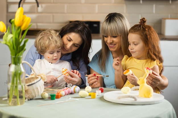 Due madri aiutano i loro figli a dipingere le uova di Pasqua