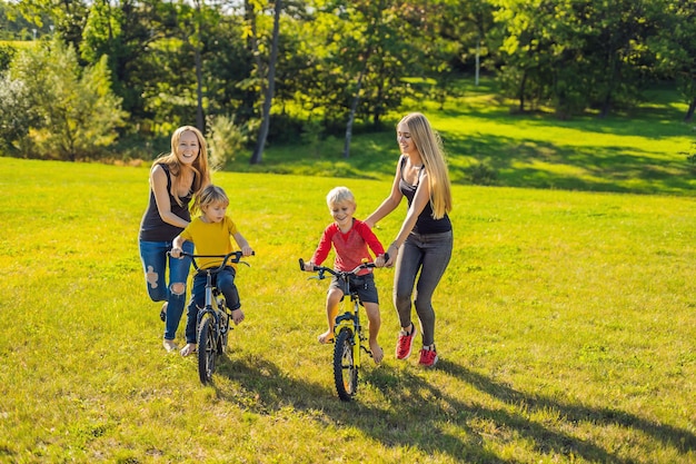 Due madri felici insegnano ai loro figli felici ad andare in bicicletta.