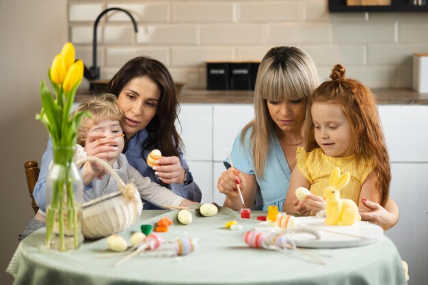 Due mamme con i loro bambini che colorano le uova di Pasqua