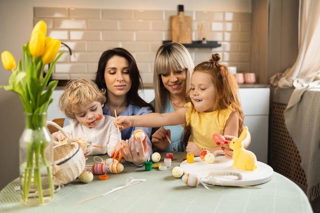 Due mamme con i loro bambini decorano le uova di Pasqua