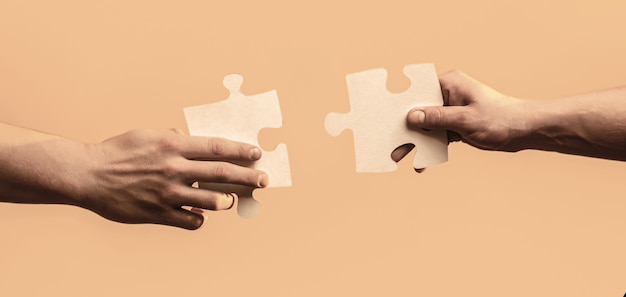 Due mani che cercano di collegare il puzzle delle coppie con sfondo giallo. Mani del primo piano dell'uomo che collega il puzzle.