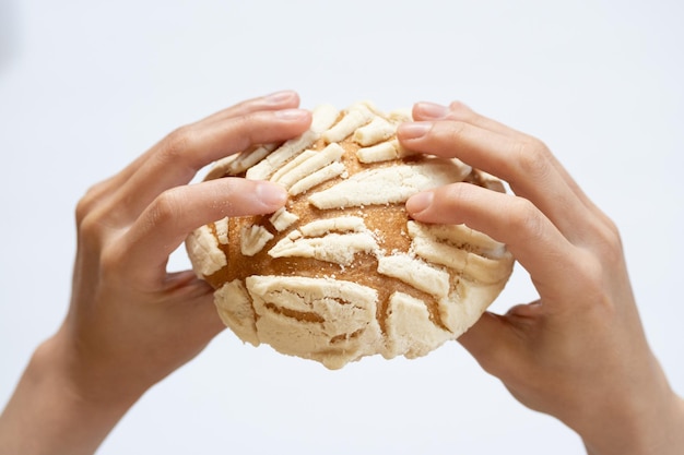 Due mani che tengono un conchas messicano su sfondo bianco