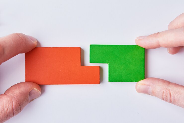 Due mani collegano i pezzi del puzzle su bianco