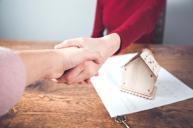 Due mani di donna modello di casa con documenti