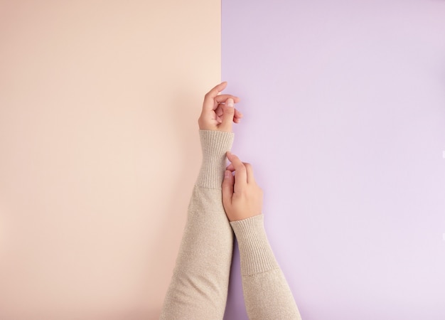 Due mani femminili con la pelle liscia chiara su uno sfondo verde rosa