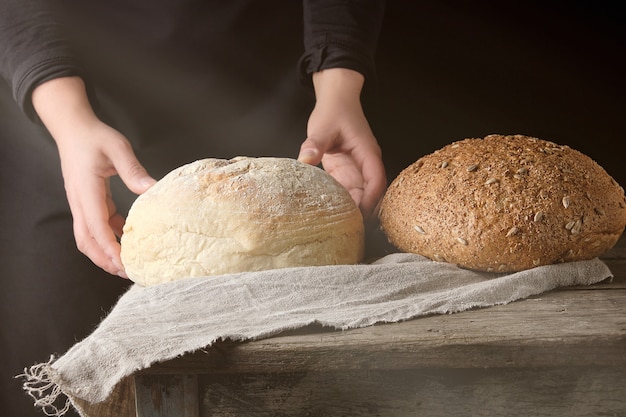 Due mani femminili giacevano su un tavolo di pane bianco tondo al forno fatto con farina di grano bianco