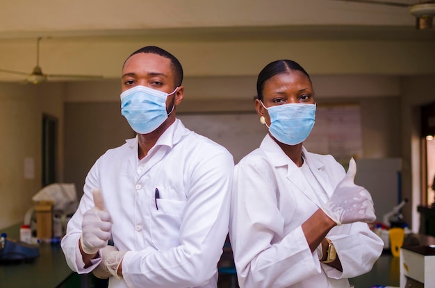 Due medici africani in piedi fianco a fianco in laboratorio hanno fatto il pollice in su