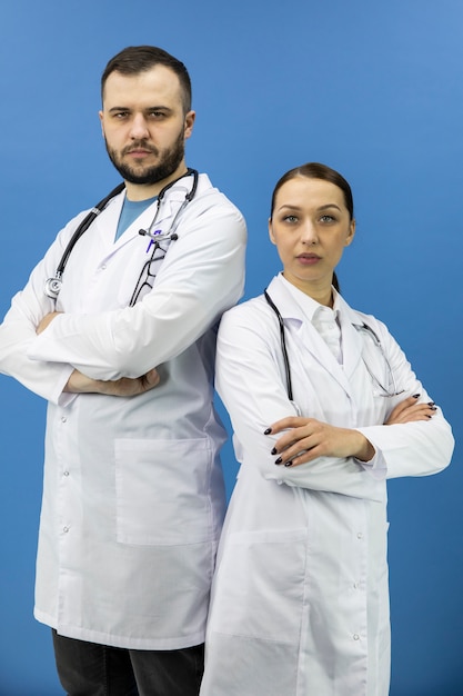 Due medici professionisti in piedi con le braccia incrociate e guarda la telecamera