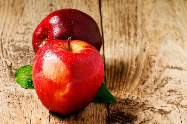 Due mele rosse con gocce d'acqua su un tavolo di legno