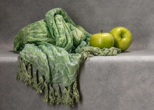 Due mele verdi su sfondo grigio Accanto a una sciarpa verde
