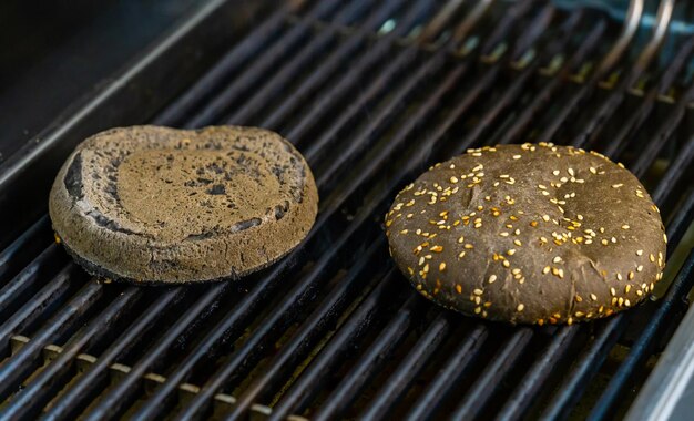 Due metà del panino nero con semi di sesamo sulla griglia Panino alla griglia per hamburger da vicino