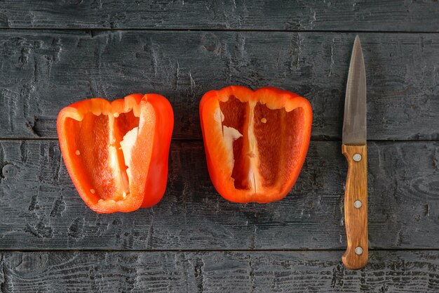 Due metà di peperone rosso e un coltello su un tavolo di legno.