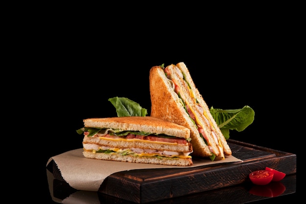 Due metà di un club sandwich su carta kraft e tagliere di legno marrone.