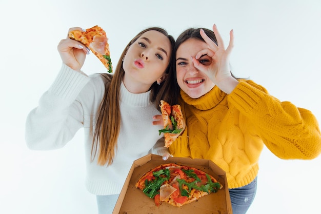 Due migliori amici che mangiano una pizza appetitosa. Ragazze sorridenti, guardando la fotocamera e in posa.