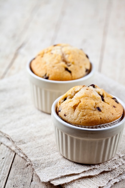 Due muffin freschi fatti in casa su ciotole di ceramica bianca sul tovagliolo di lino.