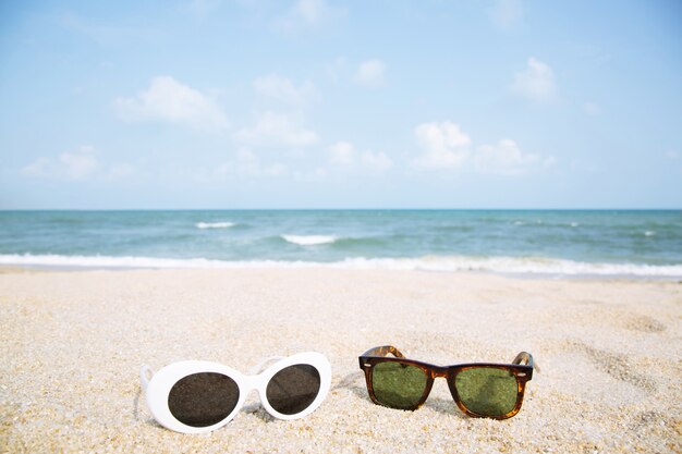 Due occhiali da sole moda si chiudono sulla sabbia della spiaggia in estate.