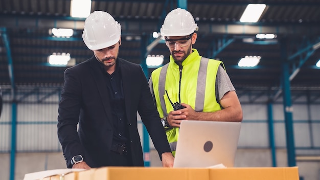 Due operai che lavorano e discutono del piano di produzione in fabbrica