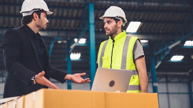 Due operai che lavorano e discutono del piano di produzione in fabbrica