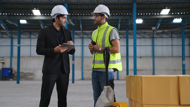 Due operai che lavorano e discutono del piano di produzione in fabbrica.