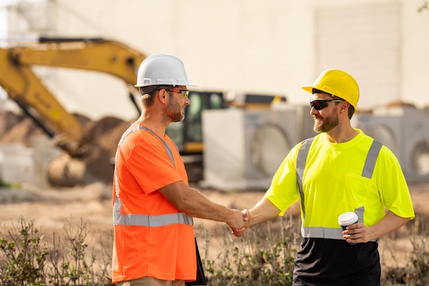 Due operai edili in casco presso i responsabili del cantiere di costruzione di edifici lavorano