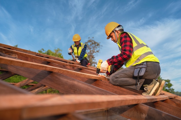 Due operai edili installano un nuovo tetto, strumenti di copertura, trapano elettrico utilizzato su nuovi tetti della struttura del tetto in legno, concetto di costruzione di lavoro di squadra.