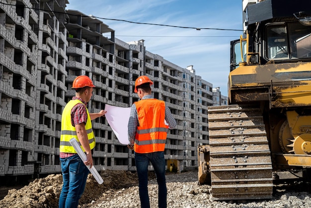 Due operai in tuta ed elmetto stanno vicino al nuovo edificio e parlano