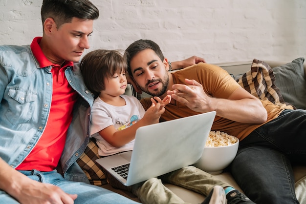 Due padri si divertono a guardare film con il figlio a casa.