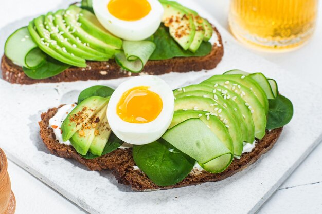 Due panini con avocado e avocado su un piatto bianco.