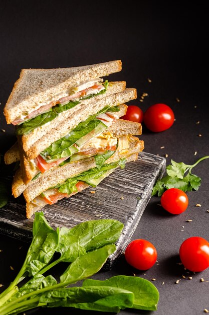 due panini di pane bianco si trovano nelle vicinanze, accanto a lattuga, pomodorini, su un taglio vintage nero