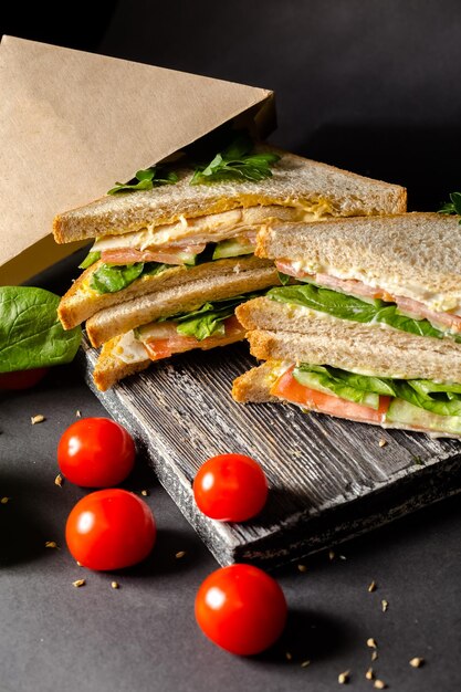 due panini di pane bianco si trovano nelle vicinanze, accanto a lattuga, pomodorini, su un taglio vintage nero