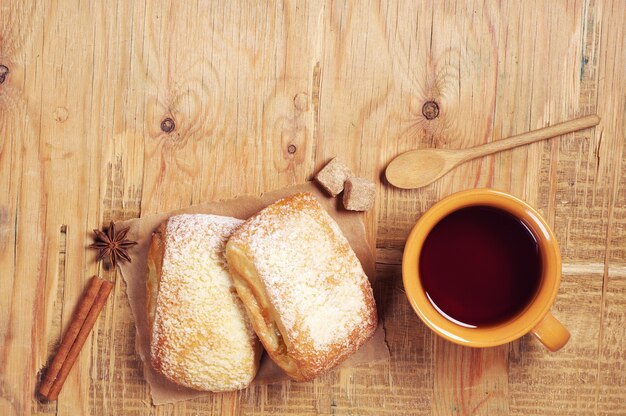 Due panini dolci e una tazza di tè sul vecchio tavolo di legno, vista dall'alto